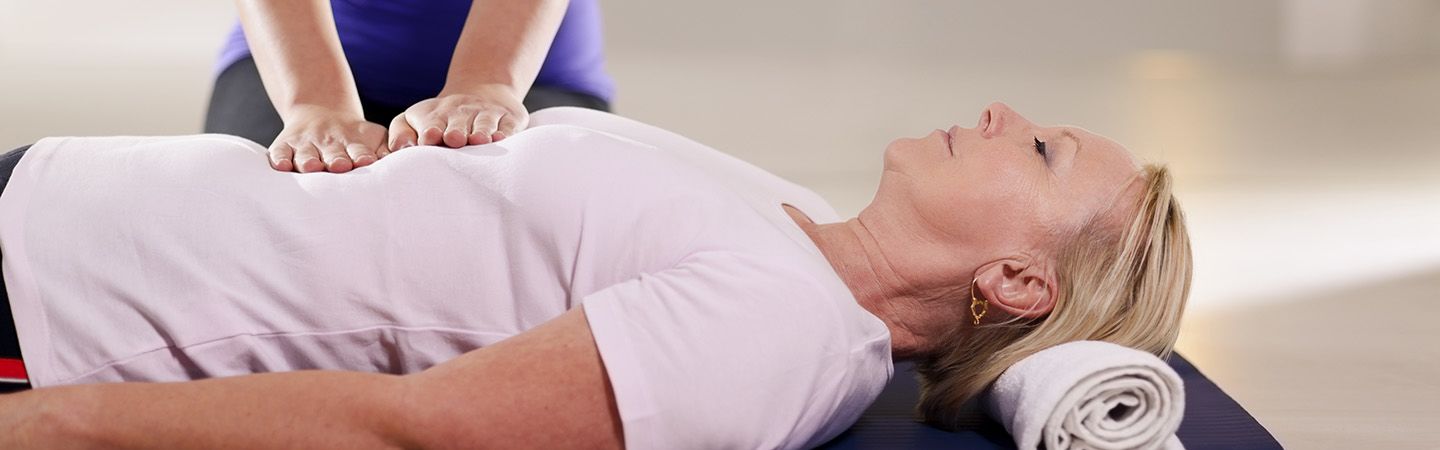 Eine ältere Frau wird auf dem Rücken am Brustkorb behandelt